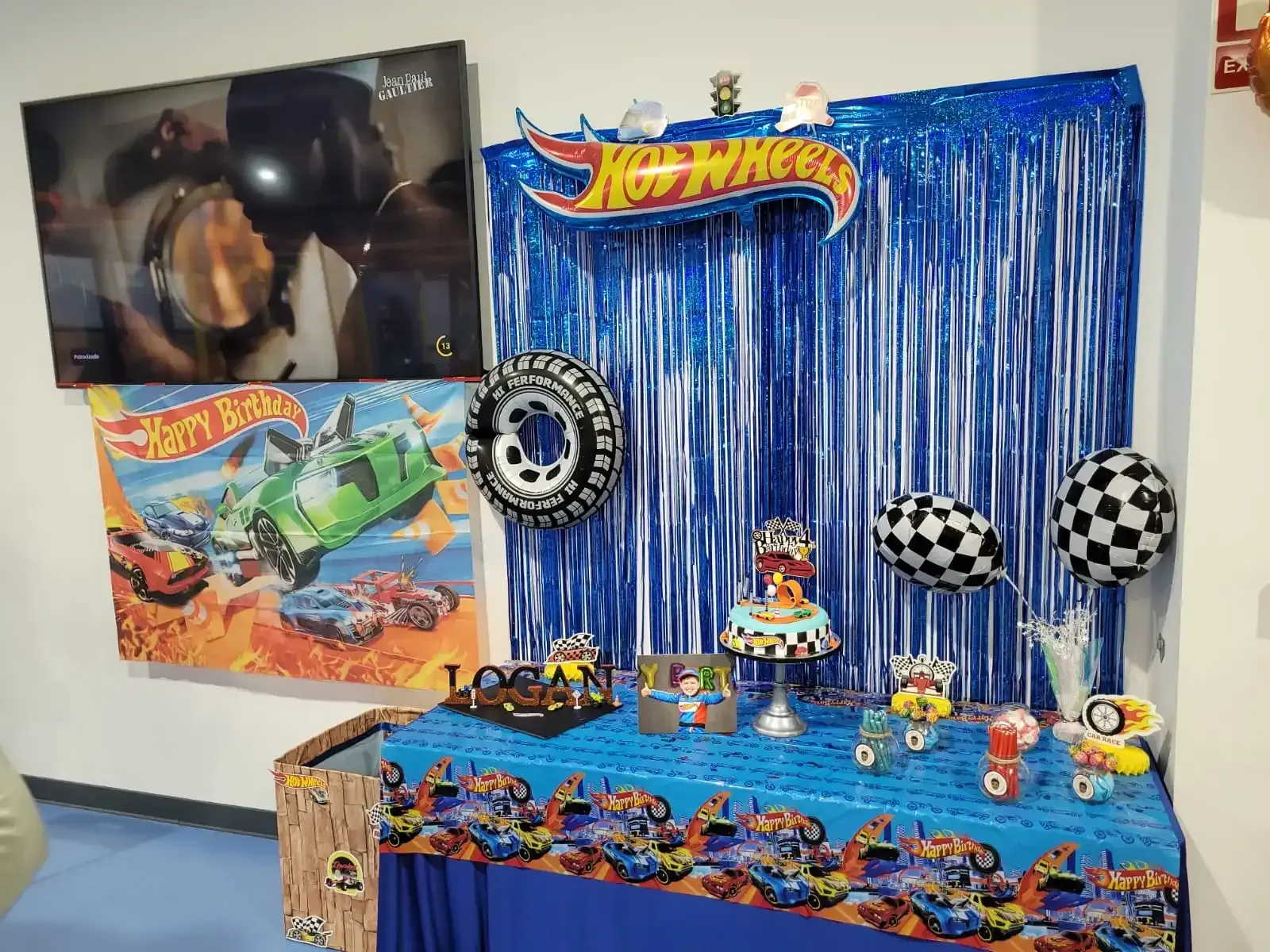 Mesa de fiesta temática de Hot Wheels con decoraciones, globos y pastel.