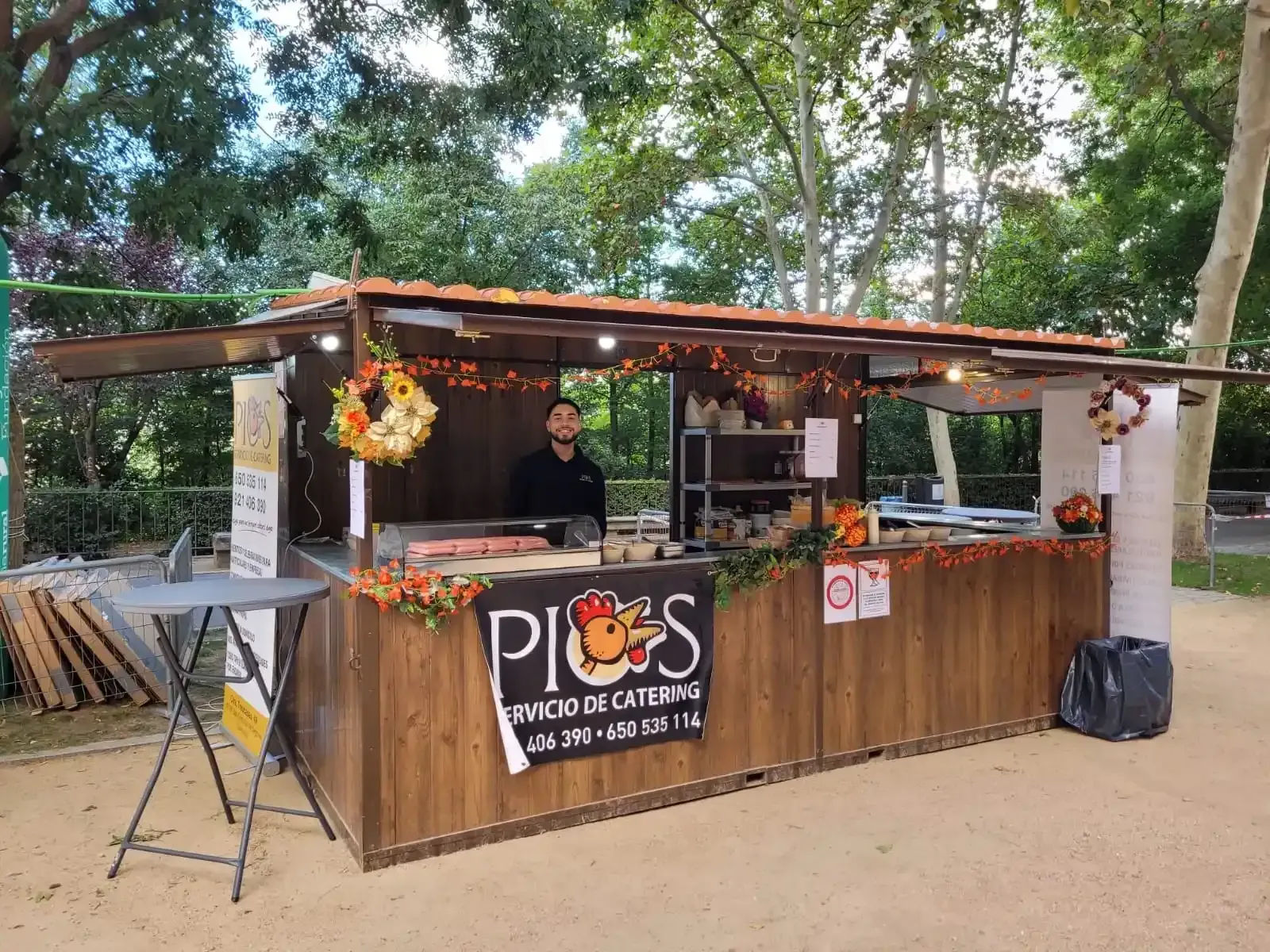 Puesto de comida en un parque; camarero detrás del mostrador con un cartel