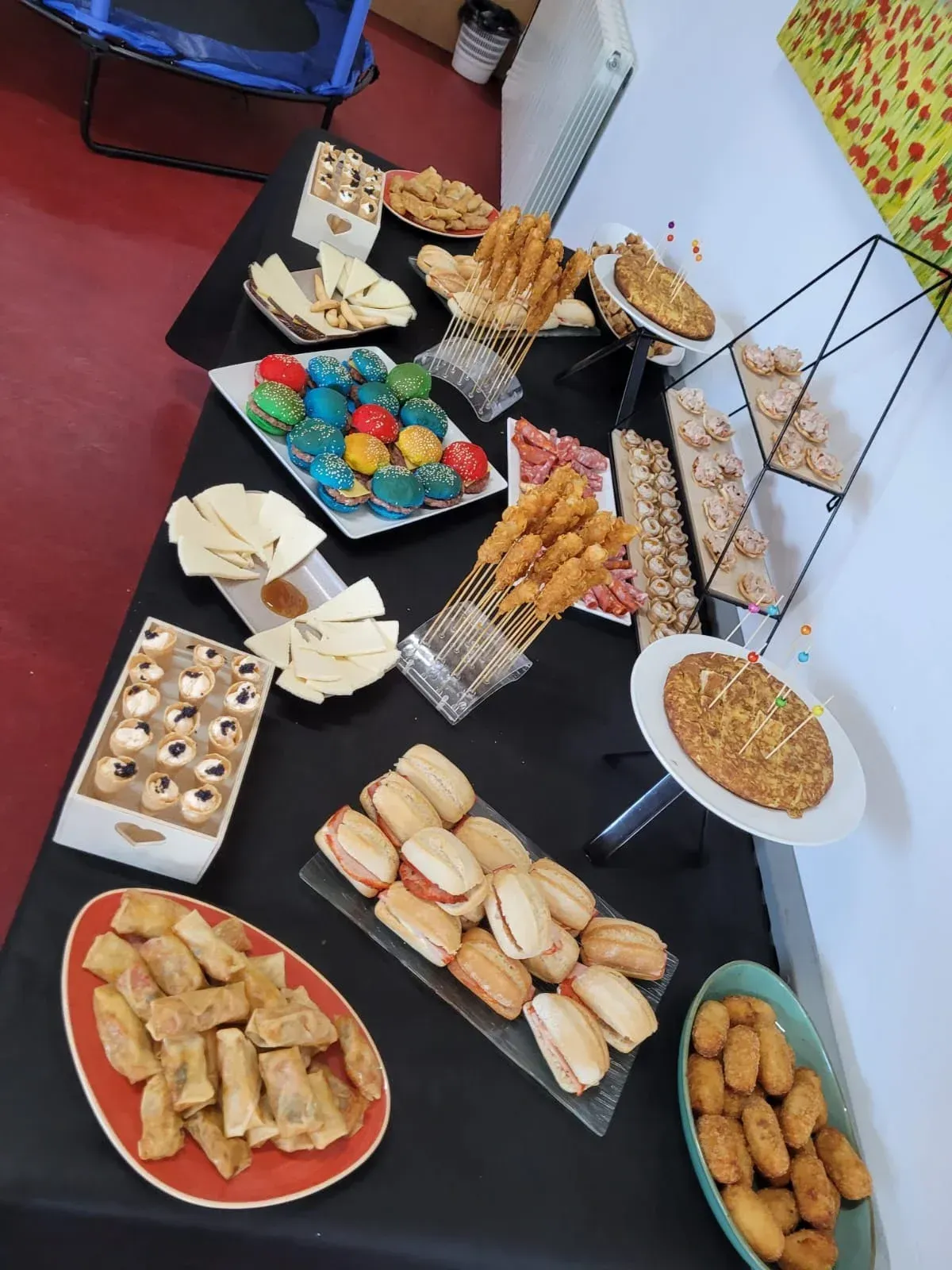Mesa buffet con diversos snacks: bollería, croquetas, bocadillos y quesos.