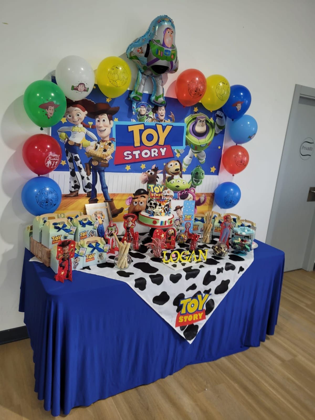 Mesa de fiesta temática de Toy Story con globos y golosinas. Colores azul y blanco.