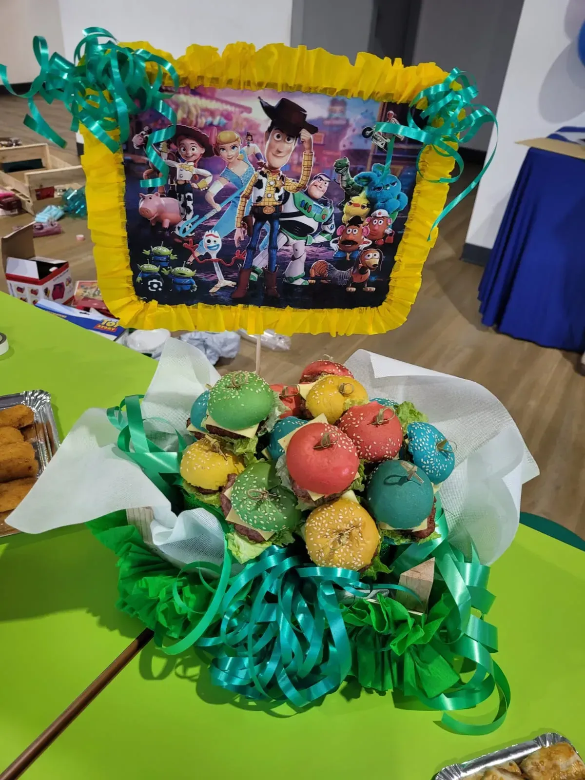 Ramo de cupcakes con temática de Toy Story con imagen del personaje, detalles verdes y amarillos, sobre una mesa verde.