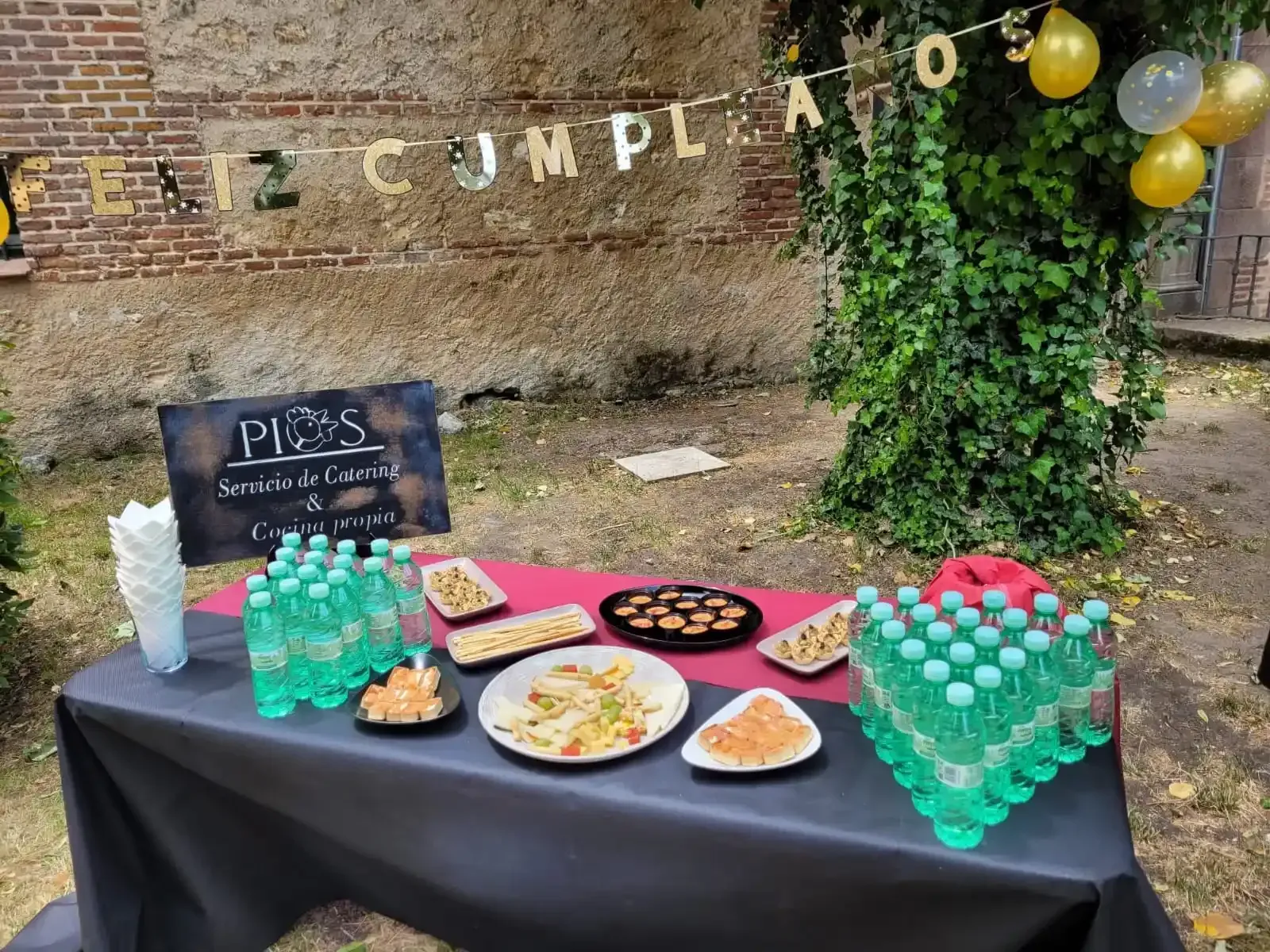 Mesa de celebración de cumpleaños con bebidas y aperitivos al aire libre. Cartel con la inscripción