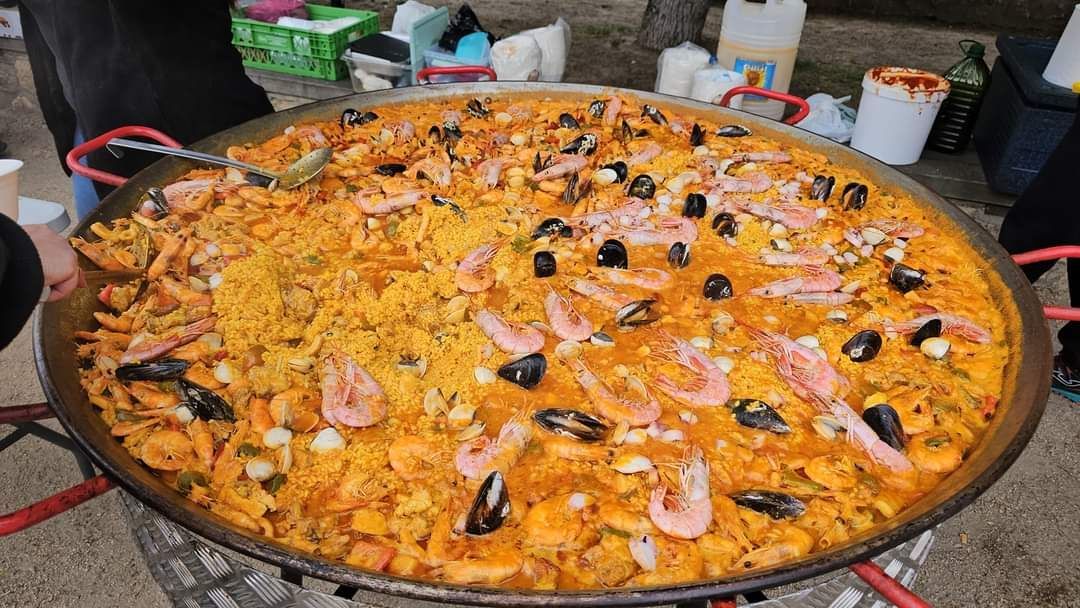 Gran paellera llena de arroz marinero al aire libre.