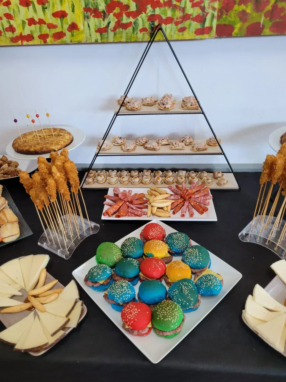 Buffet con variedad de snacks y postres, incluidos macarons, dispuestos sobre una mesa negra con exposición escalonada.