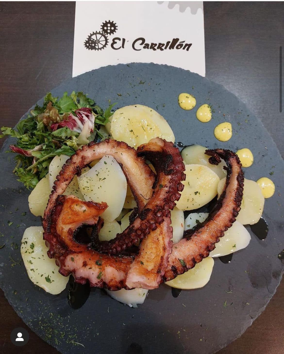 Un plato de comida con un pulpo encima de patatas.