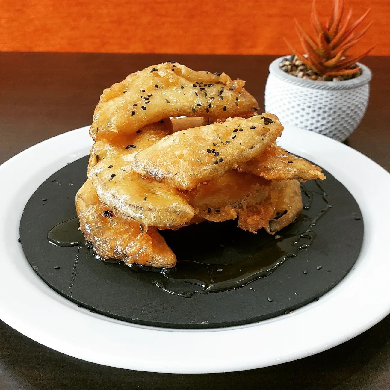 Un plato de comida con una planta al fondo.