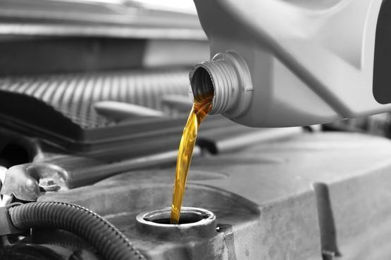 Una persona está vertiendo aceite en el motor de un automóvil.