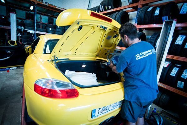 Un hombre con una camisa azul está trabajando en un coche amarillo.