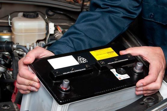 Una persona sostiene una batería de automóvil en sus manos.