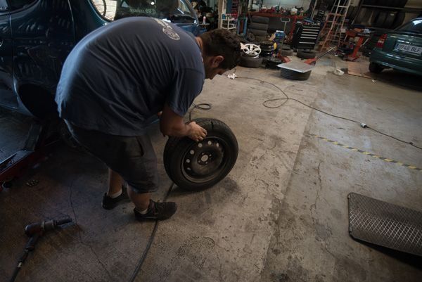 Un hombre está cambiando un neumático en un garaje.
