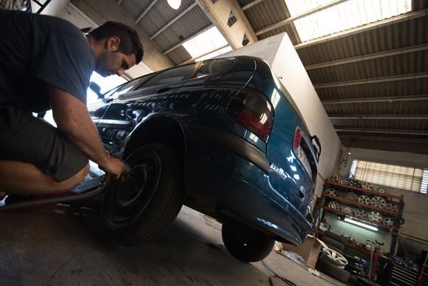 Un hombre está cambiando una llanta de un auto azul.