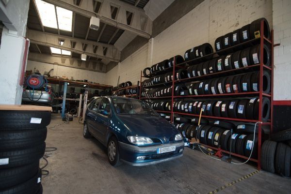 Un coche está aparcado en un garaje lleno de neumáticos.