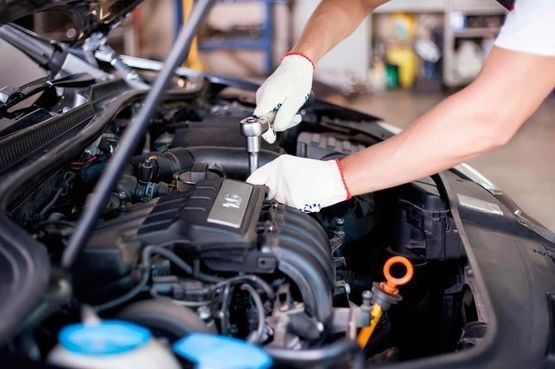 Un hombre está trabajando en el motor de un coche en un garaje.