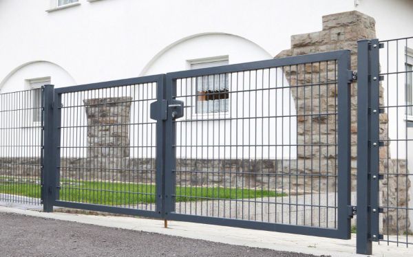 Schwarzes mehrflügeliges Zauntor-System vor einem Gebäude