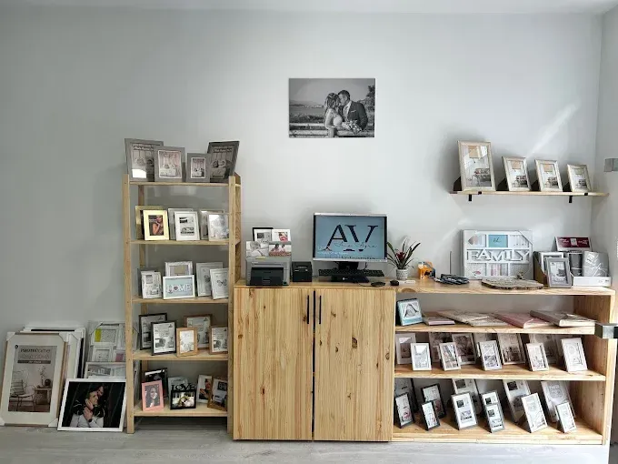 Un estudio con estanterías de madera que exhiben varias fotografías enmarcadas, un monitor de ordenador y álbumes de fotos.