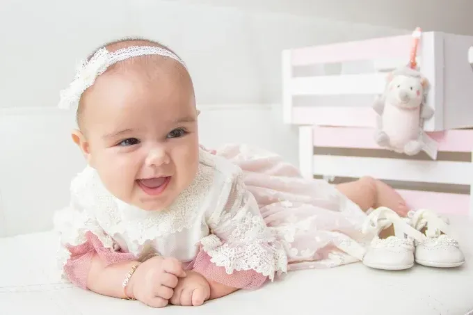 Un bebé sonriente con un vestido