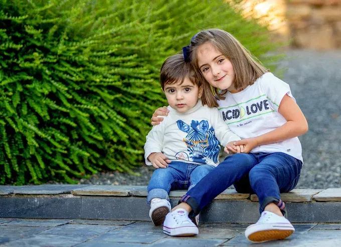 Dos niños están sentados juntos al aire