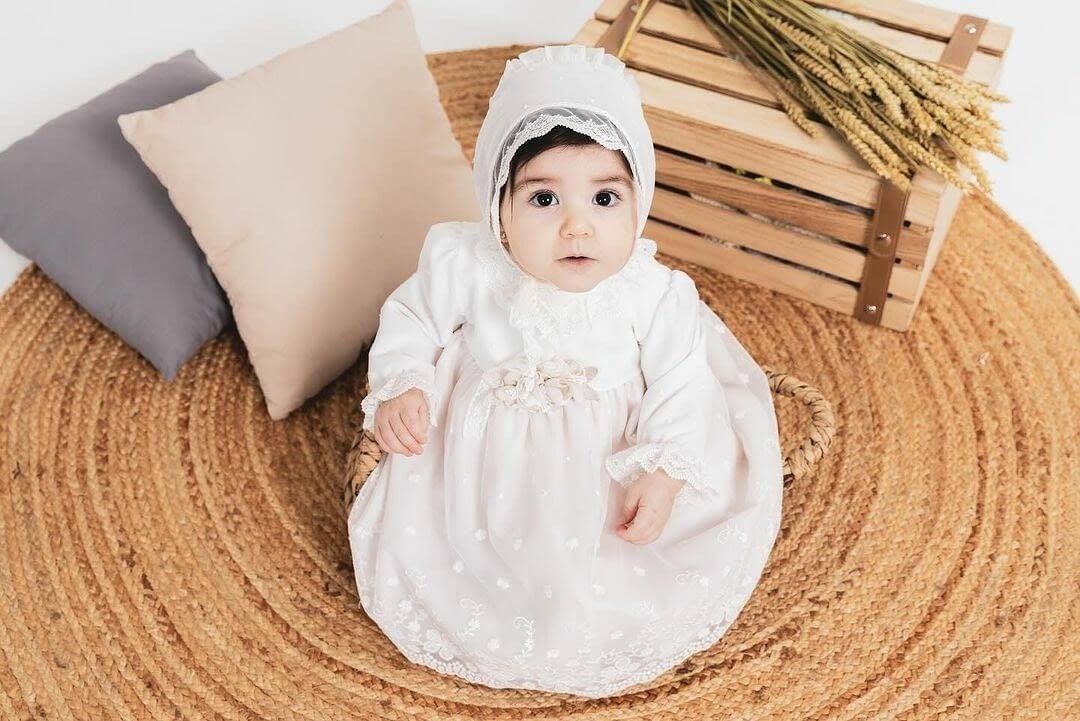 Un bebé con un gorrito y un vestido