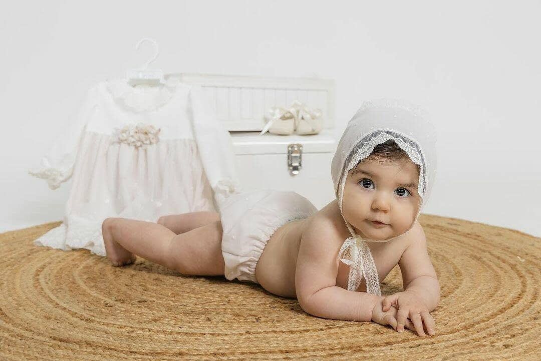 Un bebé con un gorrito de encaje yace