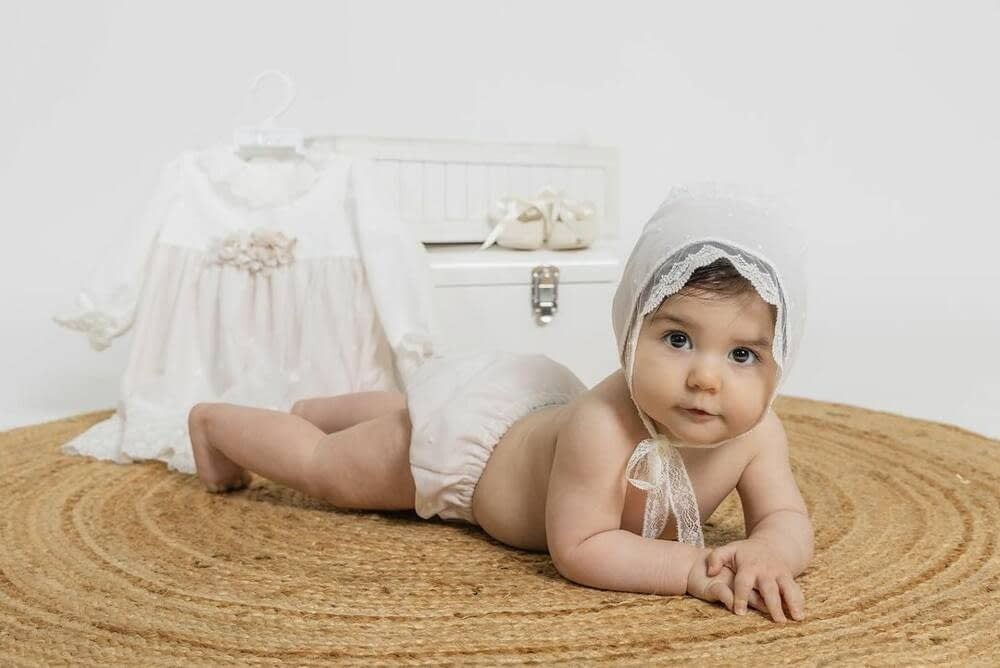 Una persona vestida con una bata de satén blanco y un peinado trenzado mira por la ventana.