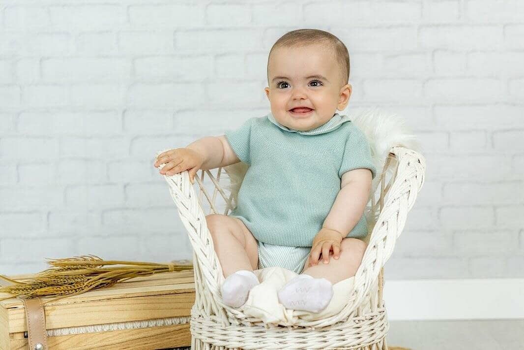 Un bebé con un conjunto de punto verde