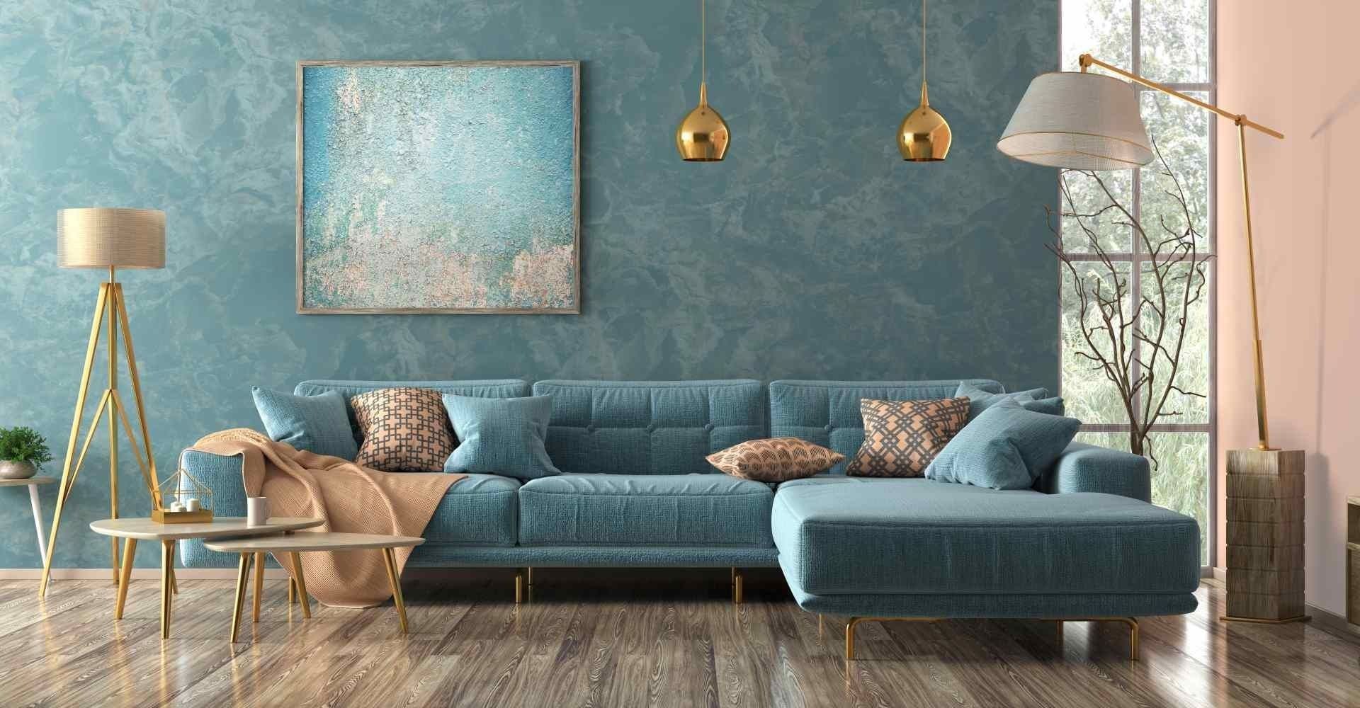 Blaugrünes Sofa in einem modernen Wohnzimmer mit goldenen Akzenten und einer blau strukturierten Wand.