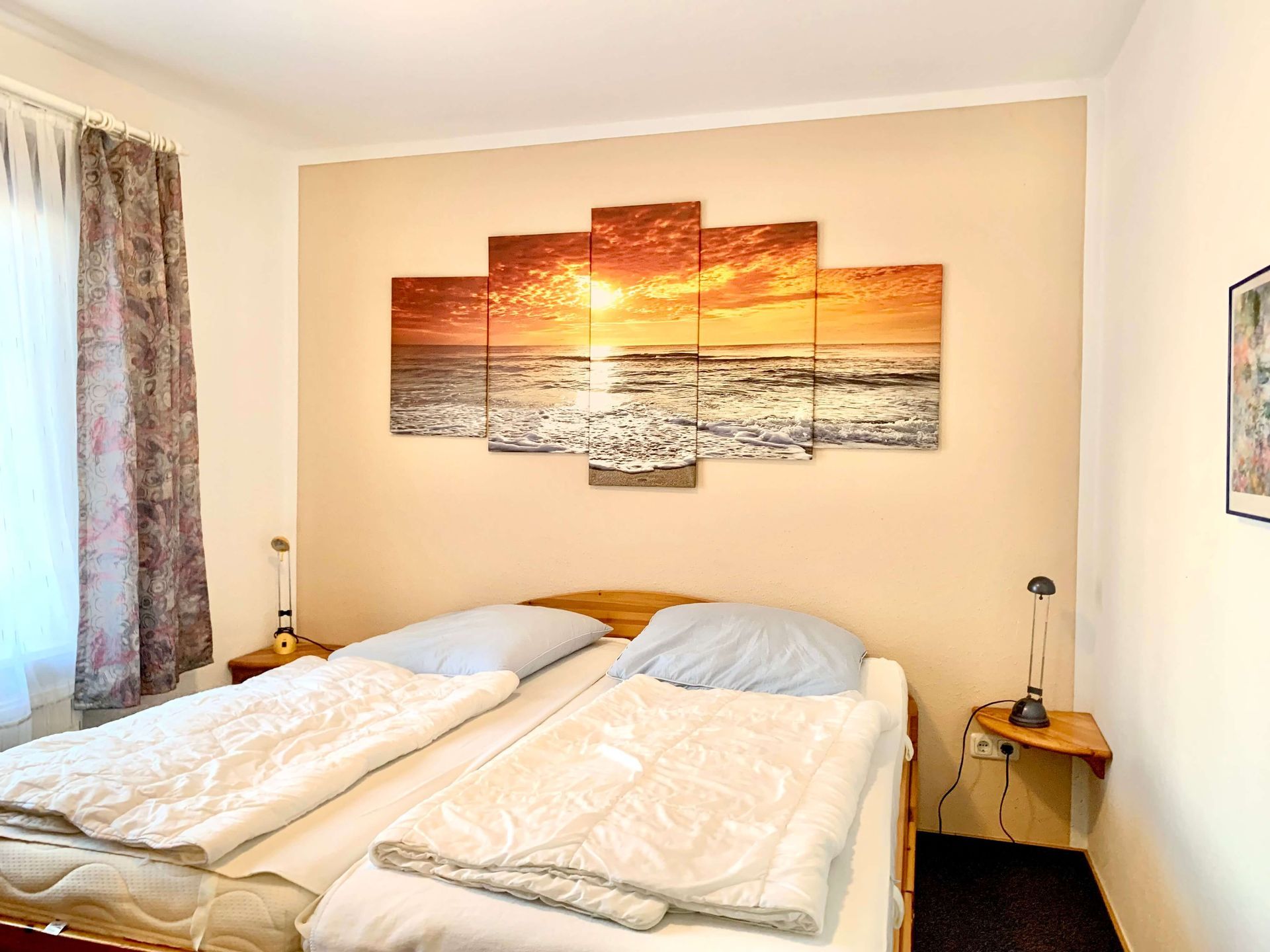 Ferienwohnung Bernstein im Haus Aquamarin in Büsum – Schlafzimmer mit Doppelbett und mit maritimem Sonnenuntergang-Wandbild