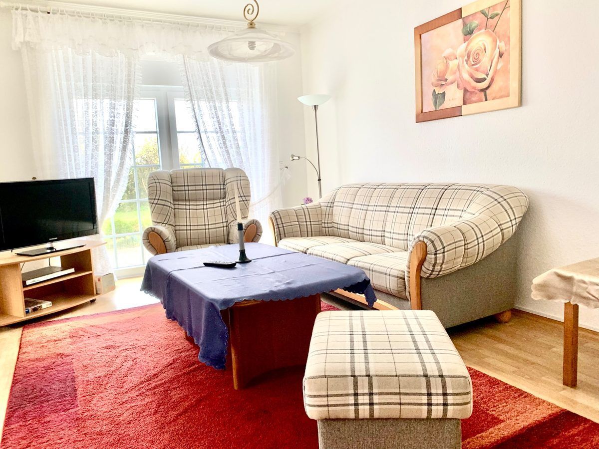 Ferienwohnung Rubin im Haus Aquamarin in Büsum – Gemütlicher Wohnbereich mit Couchgarnitur und Fernseher