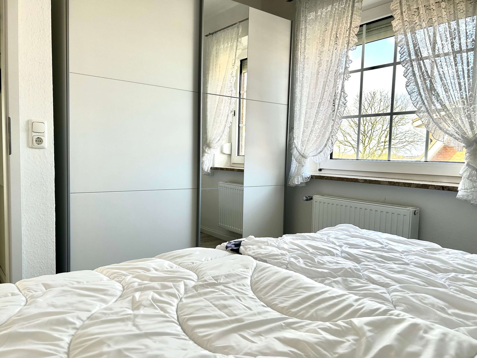 Ferienwohnung Türkis im Haus Aquamarin in Büsum – Schlafzimmer mit Doppelbett und Kleiderschrank mit Spiegel