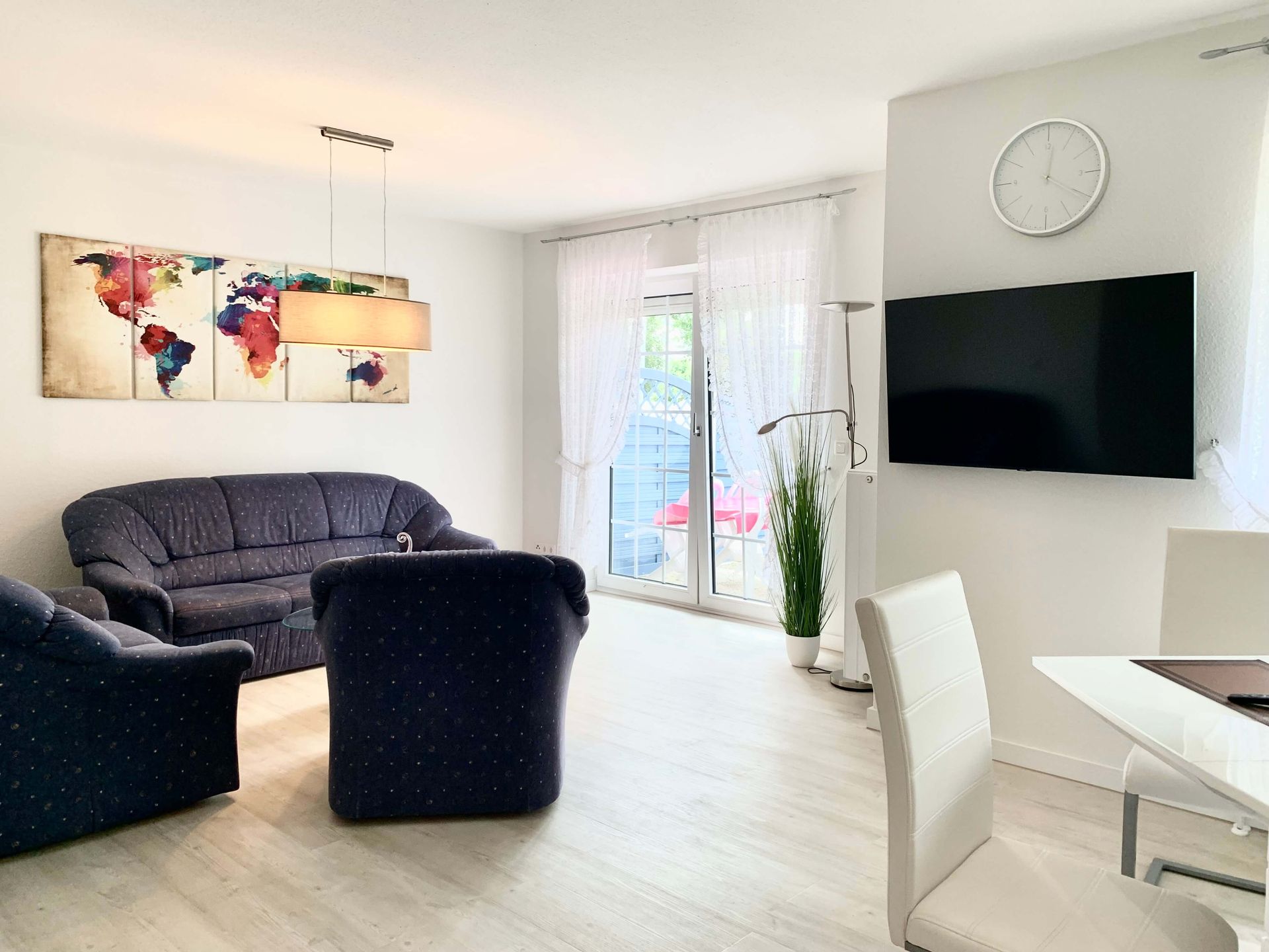 Ferienwohnung Saphir Büsum – Gemütlicher Wohnbereich mit blauer Couch und moderner Kunst.