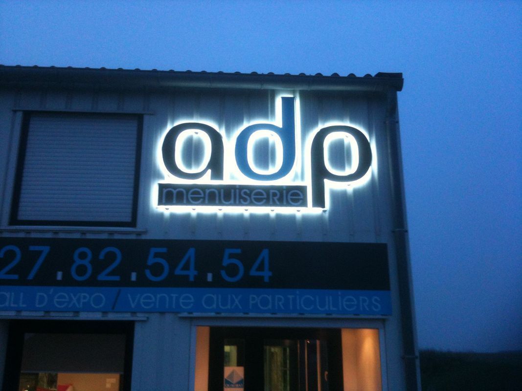 Devanture d'ADP Menuiserie allumée.