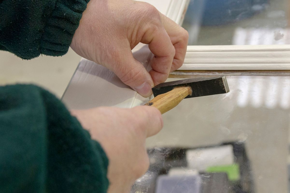 Professionnel utilisant un marteau sur un cadre de fenêtre en bois.