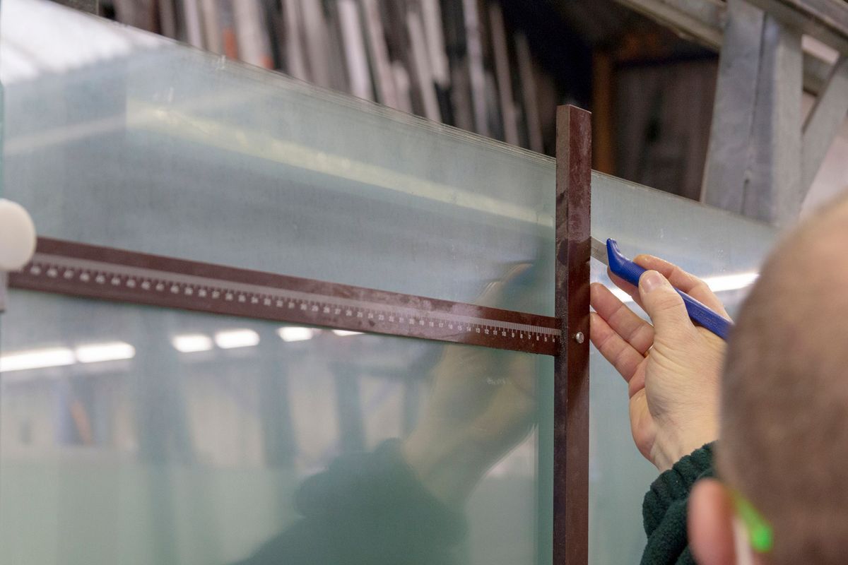 Professionnel utilisant un cutter sur des plaques de verre.