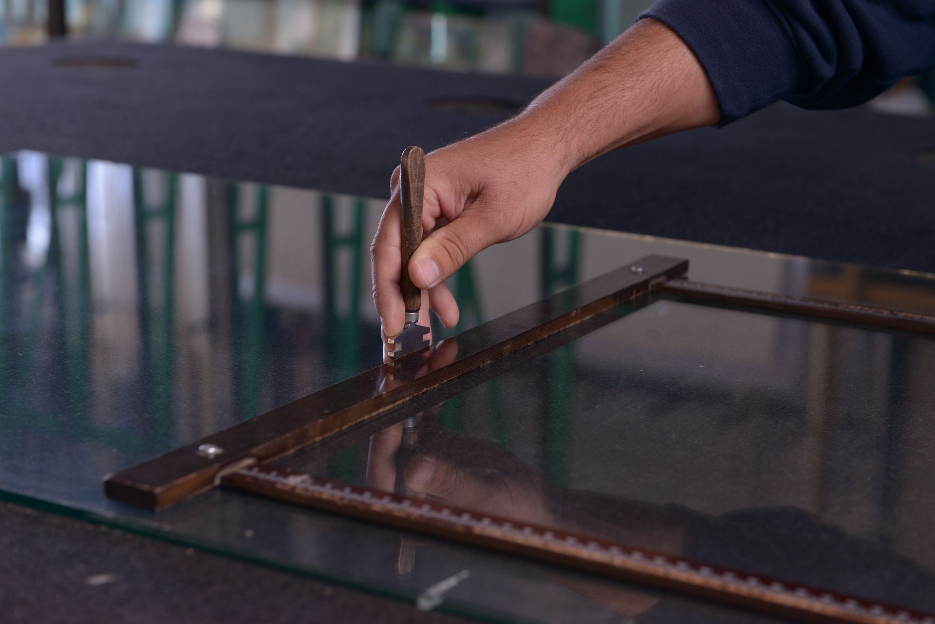 Personne utilisant un outil pour découper une plaque de verre.