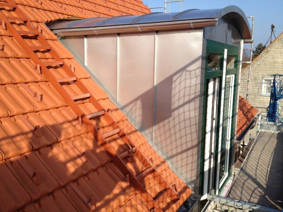 Dach mit orangefarbenen Ziegeln und ein Dachgaubenfenster mit Glasfenstern und Metallverkleidung.