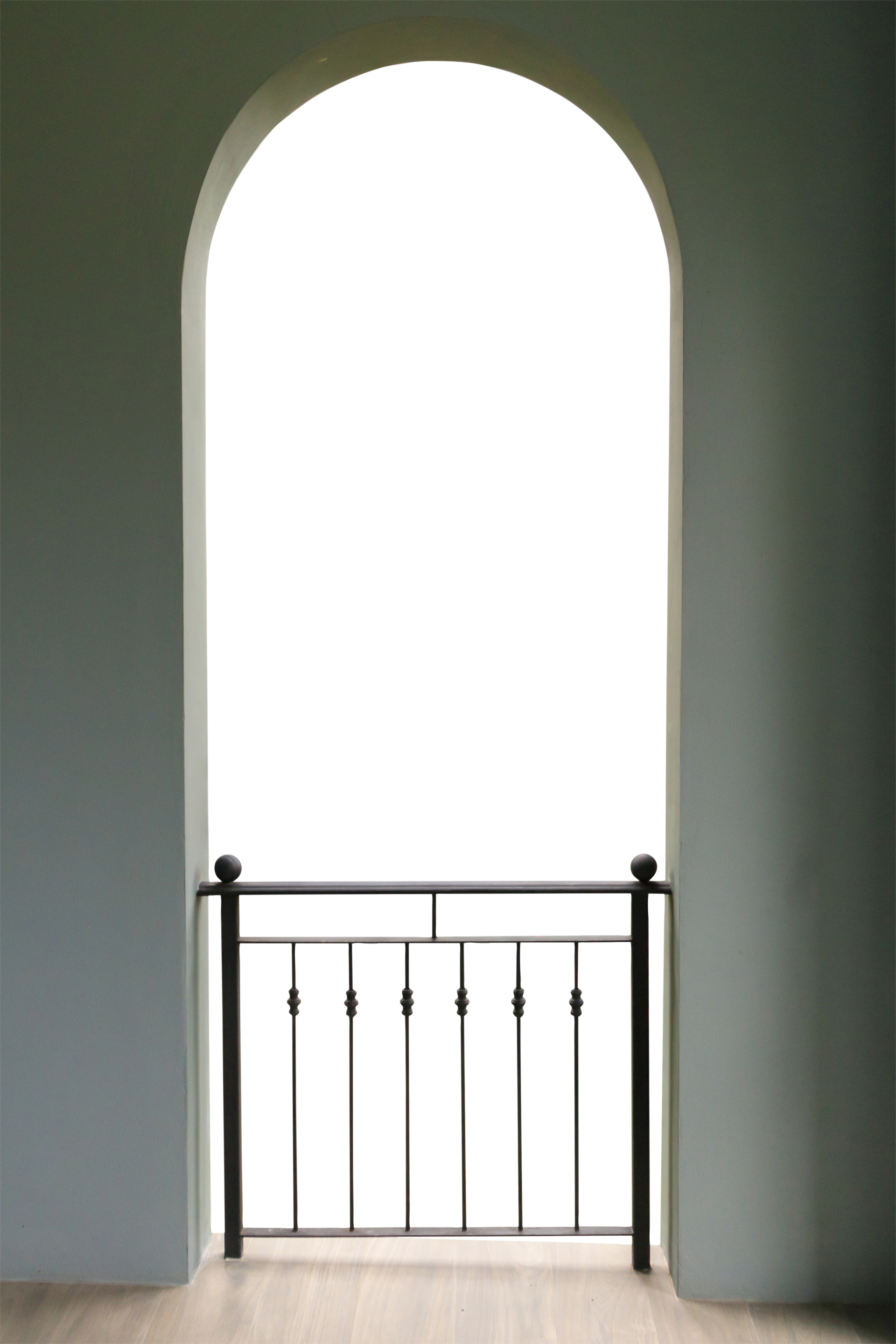 Une porte cintrée avec une balustrade en fer forgé sombre en partie basse.