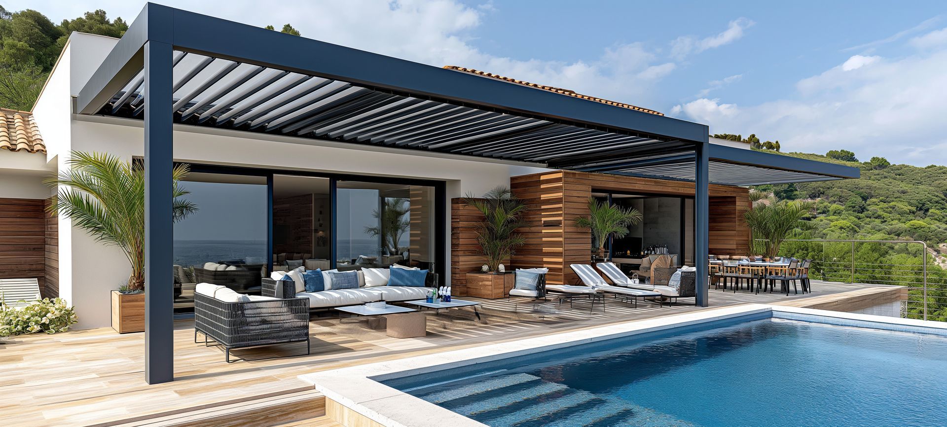 Patio de villa moderne avec pergola à toit à lames orientables, mobilier de jardin et piscine donnant sur un paysage verdoyant.