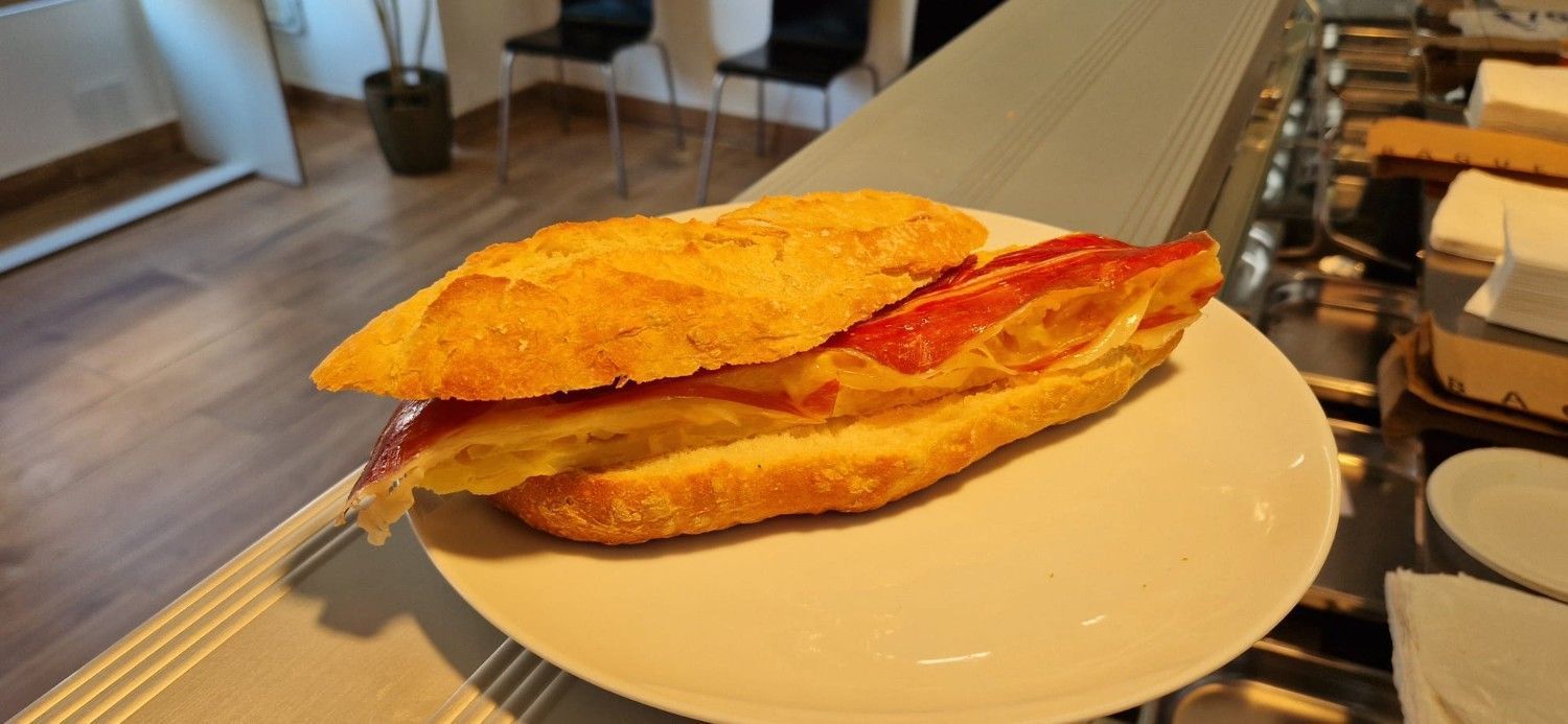 Dos sándwiches tostados en un plato blanco sobre una mesa de café.