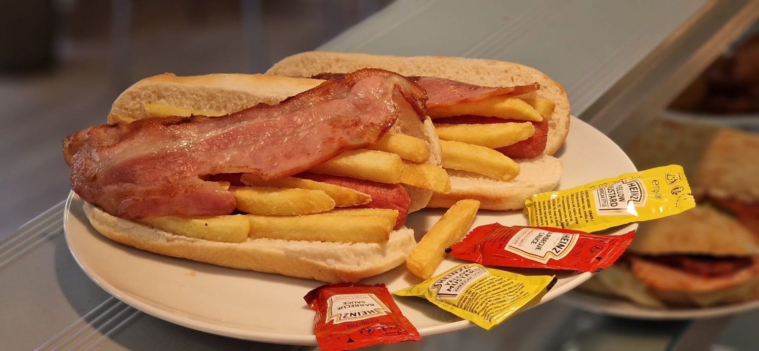 Queso fundido y carne en rodajas en un sándwich sobre una tabla de madera con papas fritas sobre una mesa.