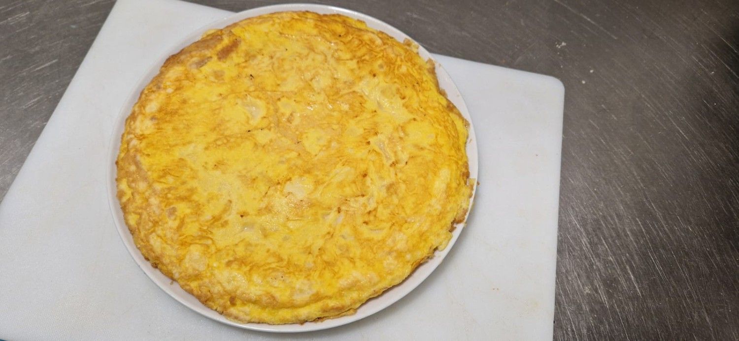 Quiche redonda dorada sobre un plato blanco en una encimera.