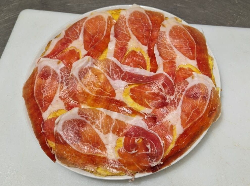 Una pizza de queso con una porción menos, sobre una tabla de madera.