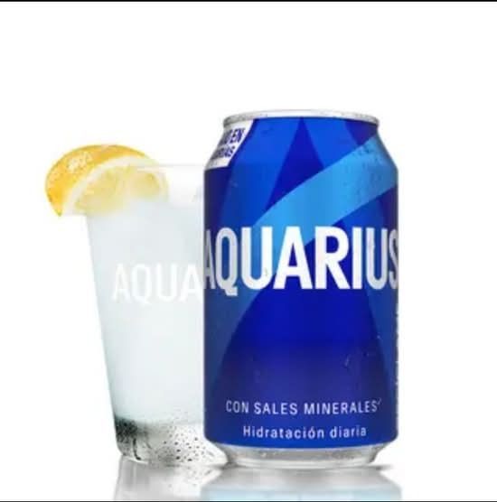 Una lata de refresco Aquarius junto a un vaso helado con una rodaja de limón.