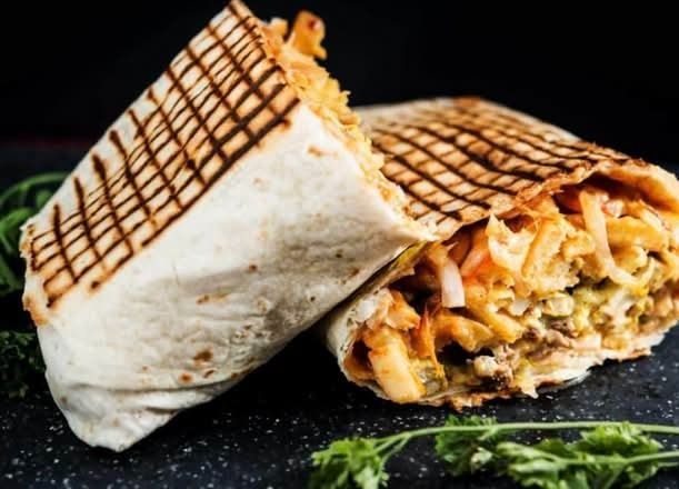 Burrito a la parrilla abierto, mostrando el relleno de queso sobre un plato oscuro con guarnición de perejil.