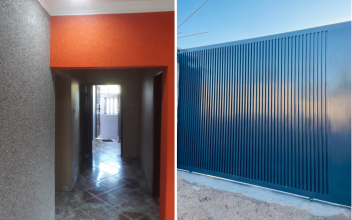 Portão deslizante de metal cinza escuro com linhas verticais, em contraste com um céu azul claro.