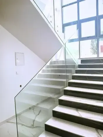 Portão deslizante de metal cinza escuro com linhas verticais, em contraste com um céu azul claro.