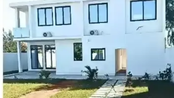 Sala de estar com parede revestida de madeira, TV sobre mármore e um vaso de planta.