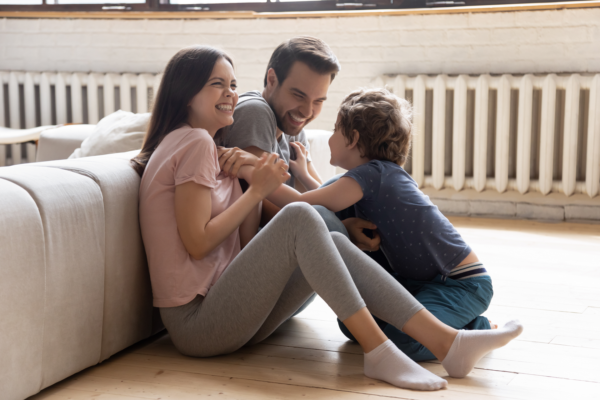 Famille jouant assise sur le parquet d'une habitation