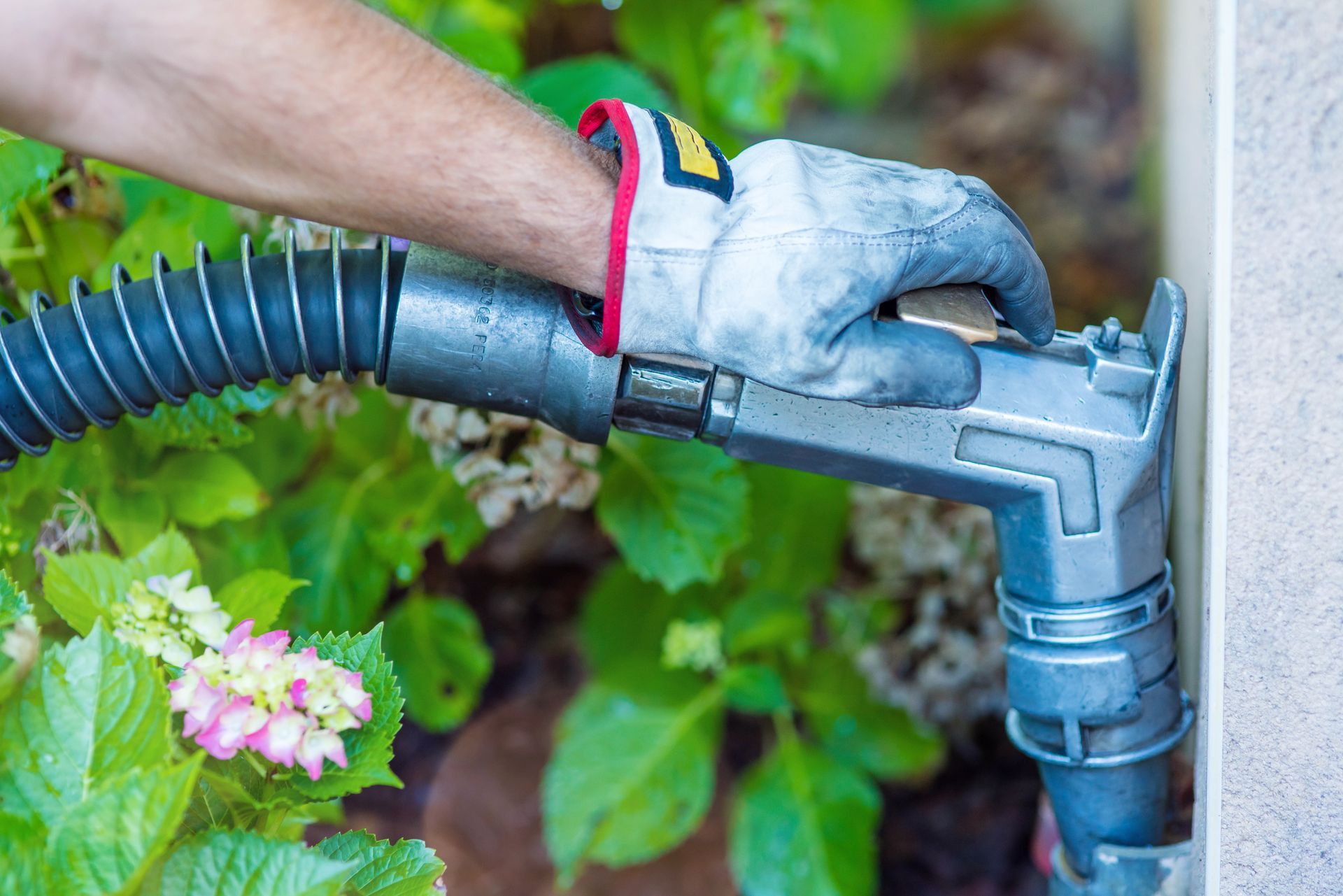 Professionnel portant un gant dans un jardin versant du fioul dans une habitation