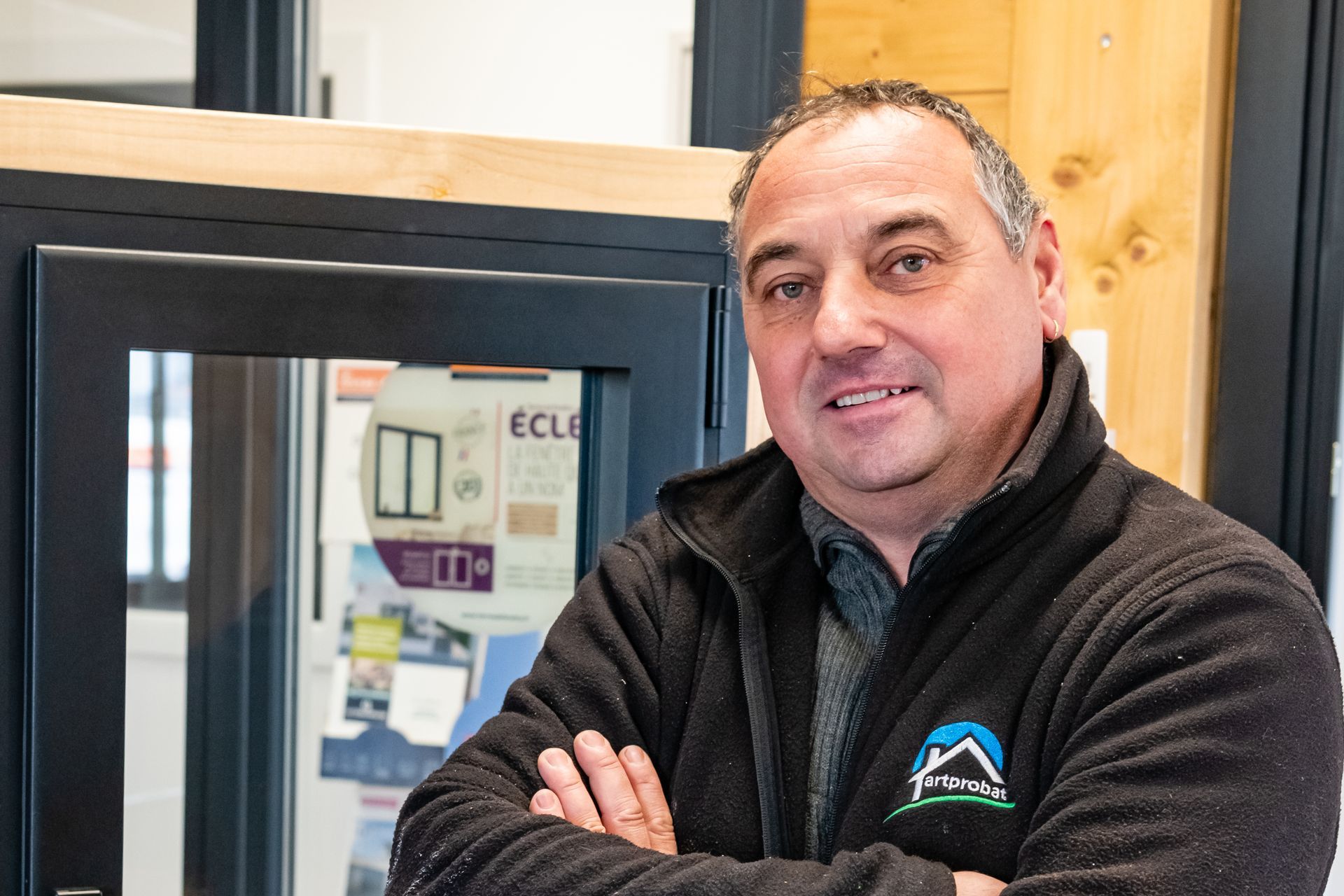 Un quatrième homme souriant croisant ses bras de chez Artprobat.