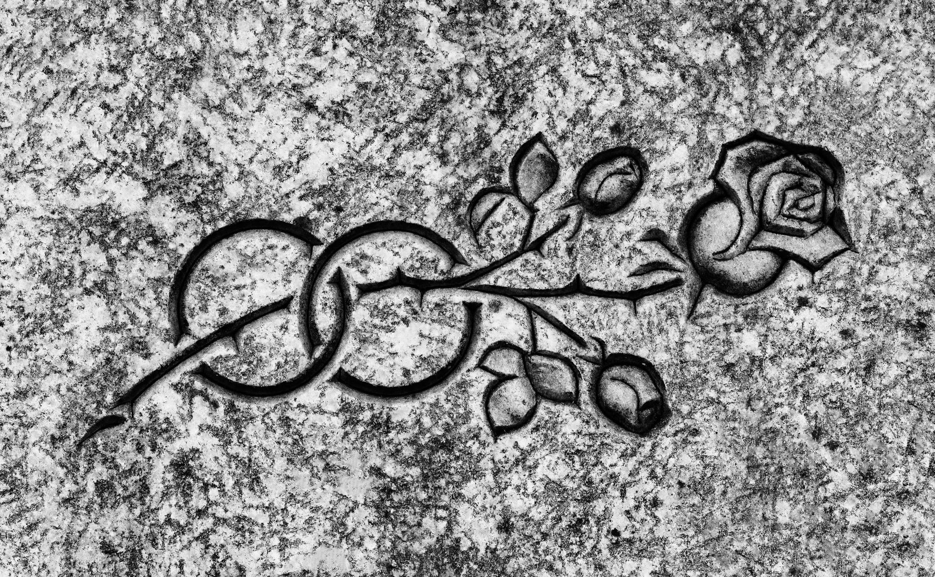 Gros plan en noir et blanc d'une rose sculptée et d'un motif de nœud celtique sur une surface texturée.